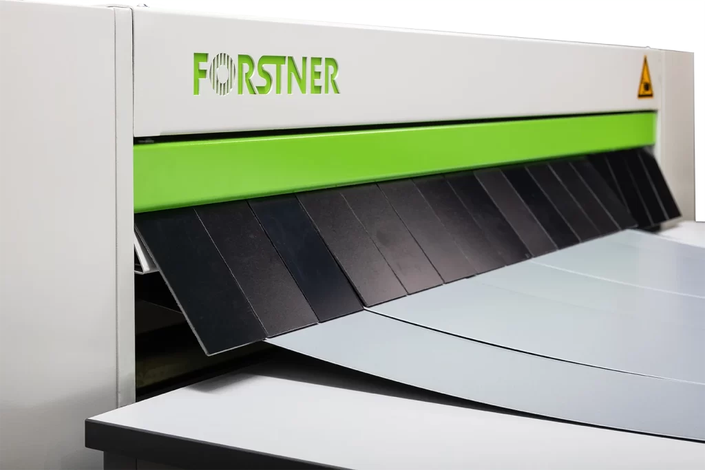 plåt klipps av en gradsax bakom en skyddsridå i forstner nuslit mot vit bakgrund